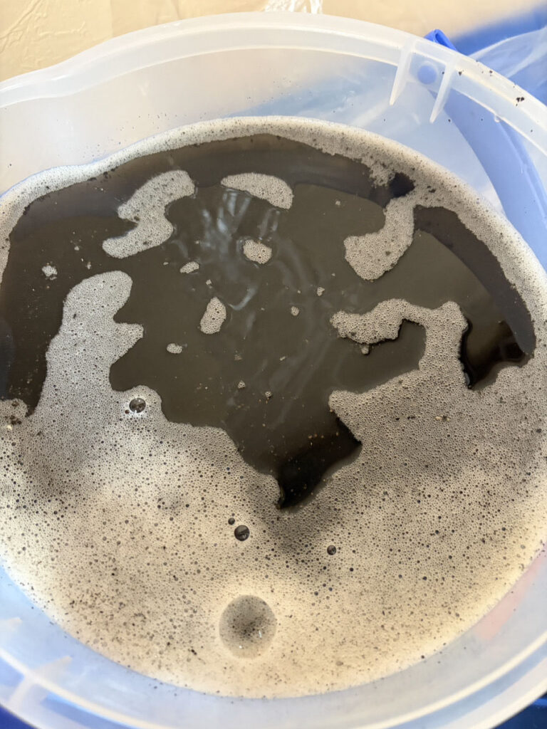 エアコンクリーニングの廃水。墨汁のように黒く汚れている