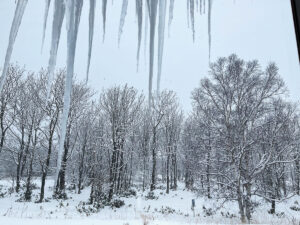 北海道の冬。屋根から氷柱が下がり、外は雪が降り積もっている。